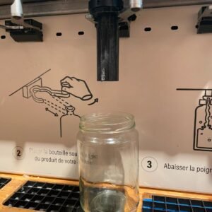 Adaptateur noir imprimé en 3D monté sur un distributeur vrac de lessive, bocal en verre dessous