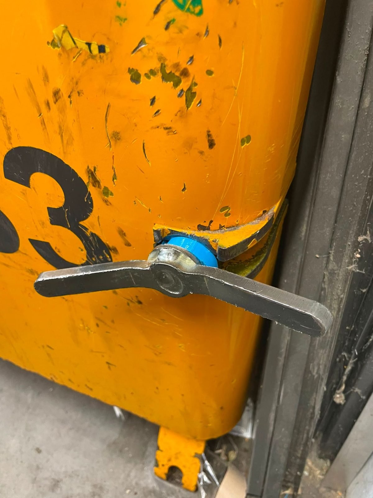Bague bleue imprimée en 3D montée sur l’axe du levier d’un compacteur jaune
