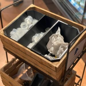 Organiseur noir à trois compartiments imprimé en 3D, encastré dans une caisse en bois, rempli de bouchons et de papier